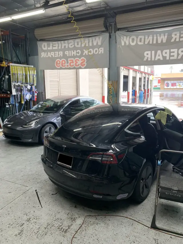 A1 Auto Glass service bay with the rock chip repair banner above two Teslas in for work
