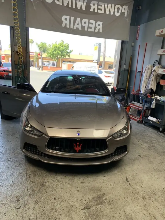 A Maserati in the A1 Auto Glass bay for power window repair under the shop banner